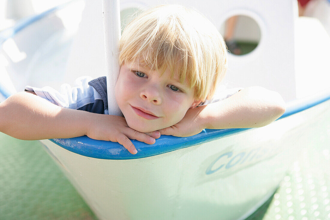 Dreamy boy in a playground boat on excursion boat, Lake Starnberg, Bavaria, Germany, MR