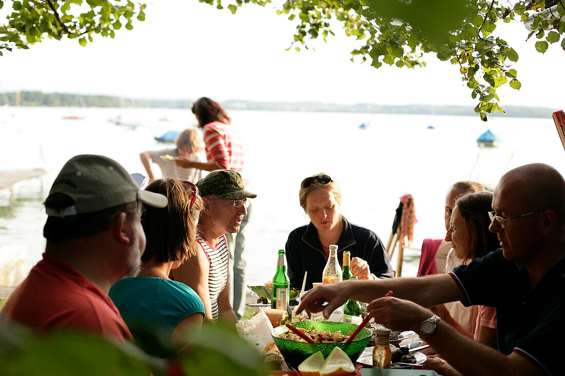 People having barbecue dinner on the lakeshore, Woerthsee, Upper Bavaria, Bavaria, Germany