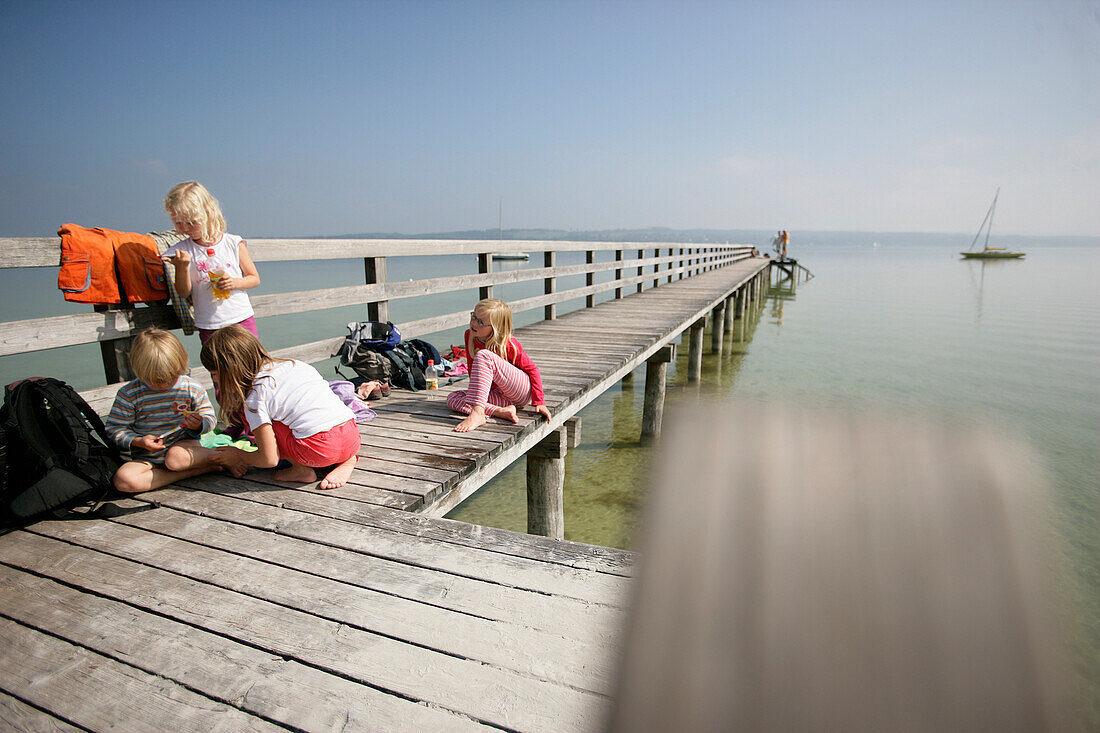 Kinder spielen auf einem Holzsteg am Ammersee, Utting, Bayern, Deutschland, MR