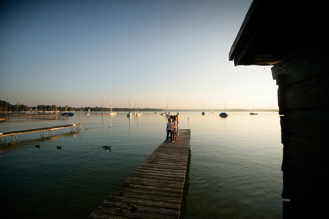 Children standing on the jetty in the evening, Lake Woerthsee, Upper Bavaria, Bavaria, Germany