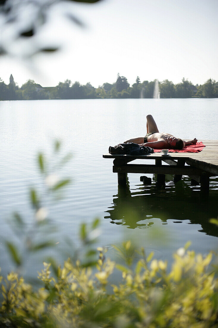 Mann beim Sonnenbaden auf einem Holzsteg, Weßlinger See, Oberbayern, Bayern, Deutschland