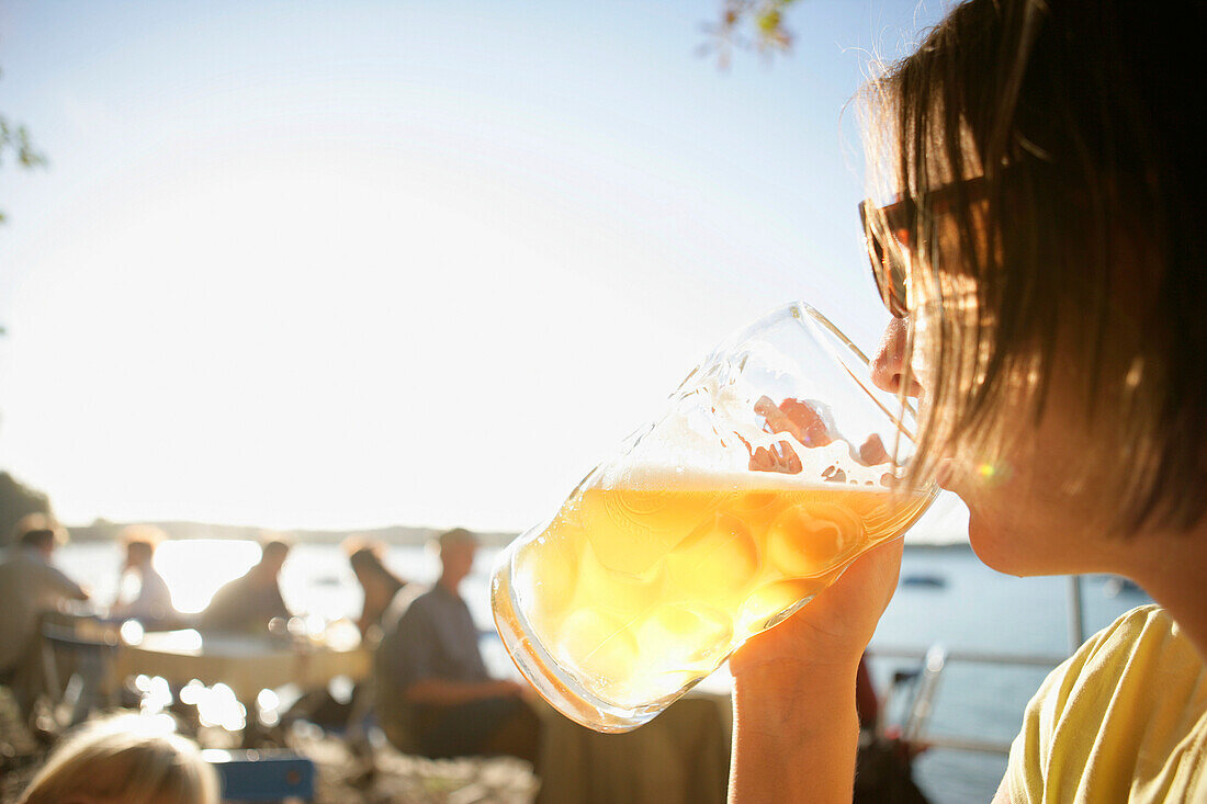 Mid adult woman drinking beer, beer garden of the restaurant Woerl, Woerthsee, Bavaria, Germany, MR