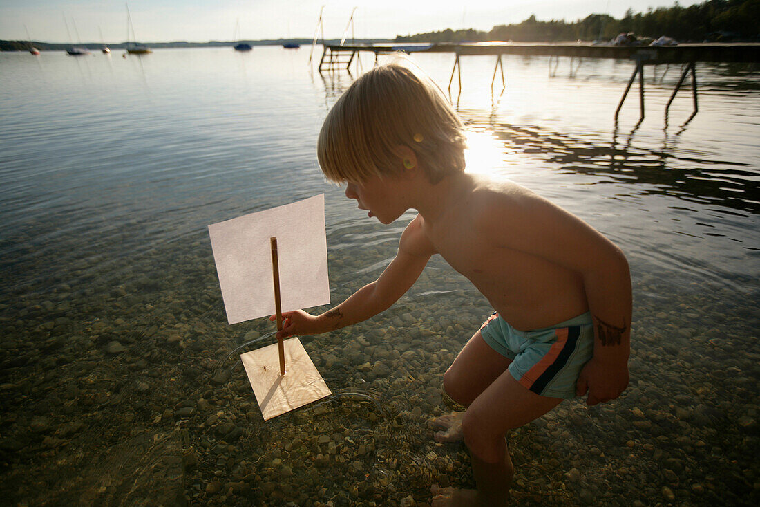 Junge spielt mit einem Floß im Wörthsee, Bayern, Deutschland, MR