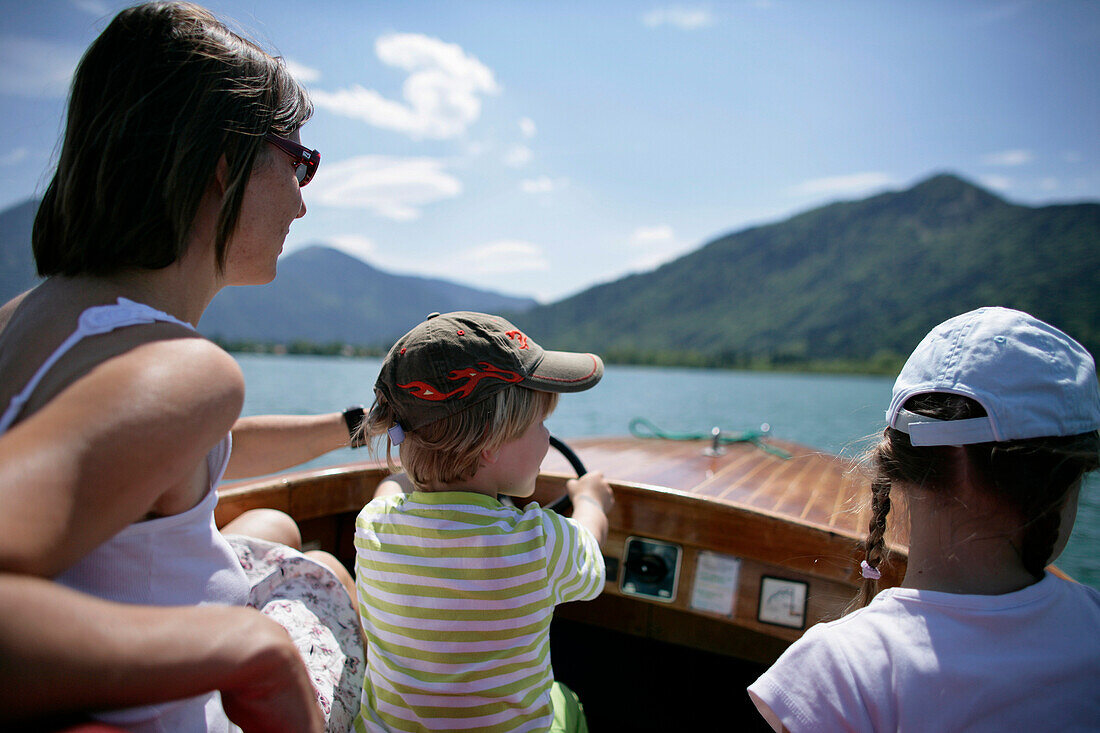 Mother and children in electric rental boat, Lake Tegernsee, Upper Bavaria, Bavaria, Germany, MR