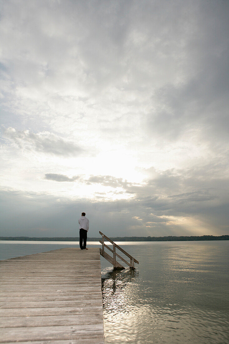 Man standing on jetty at Lake Starnberg, Muensing-St. Heinrich, Upper Bavaria, Bavaria, Germany, MR