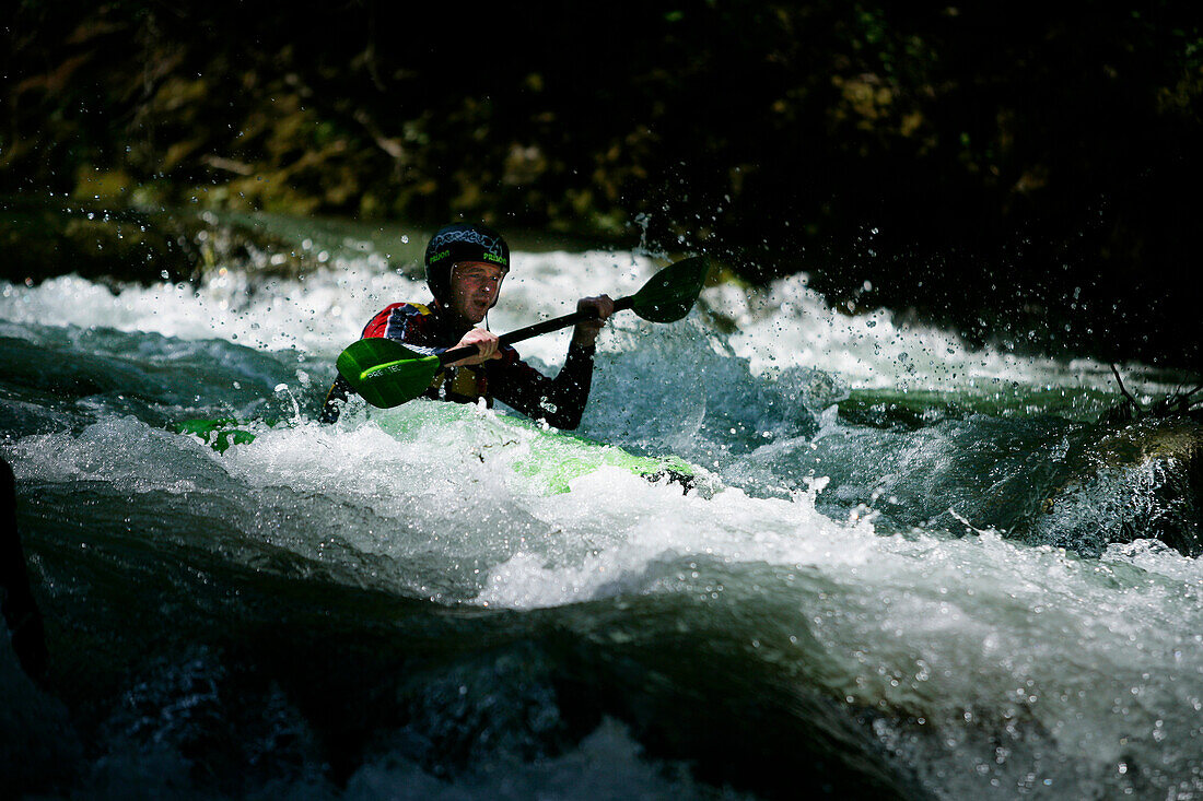 Man, guide, paddling through whitewater, kayak weekend for beginners on the Mangfall river, Upper Bavaria, Germany