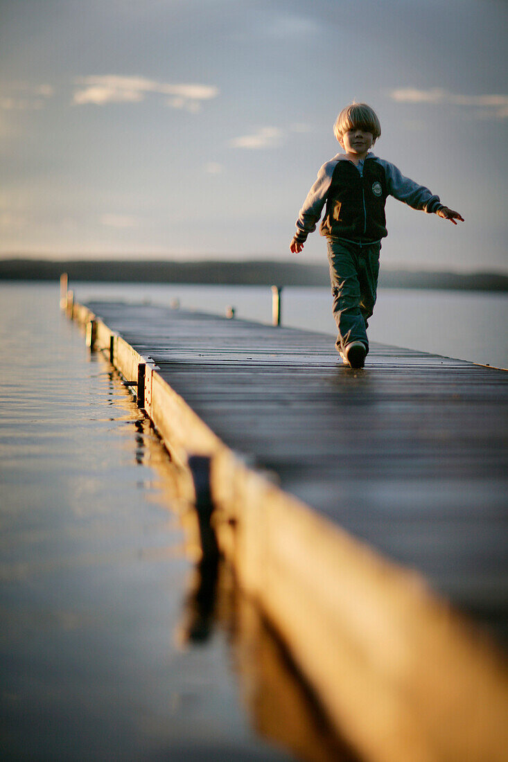 Boy (3-4 years) on jetty at Lake Starnberg, Upper Bavaria, Bavaria, Germany