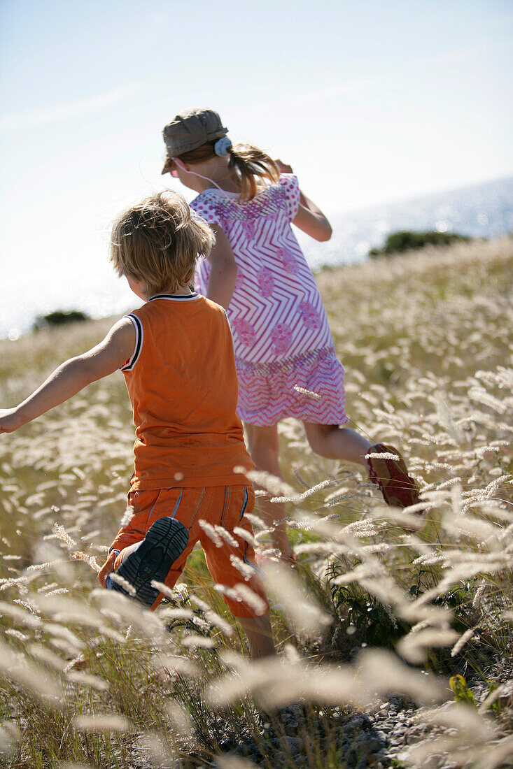 Junge und Mädchen laufen durch Wiese, Strandgrass, Sysne, Gotland, Schweden