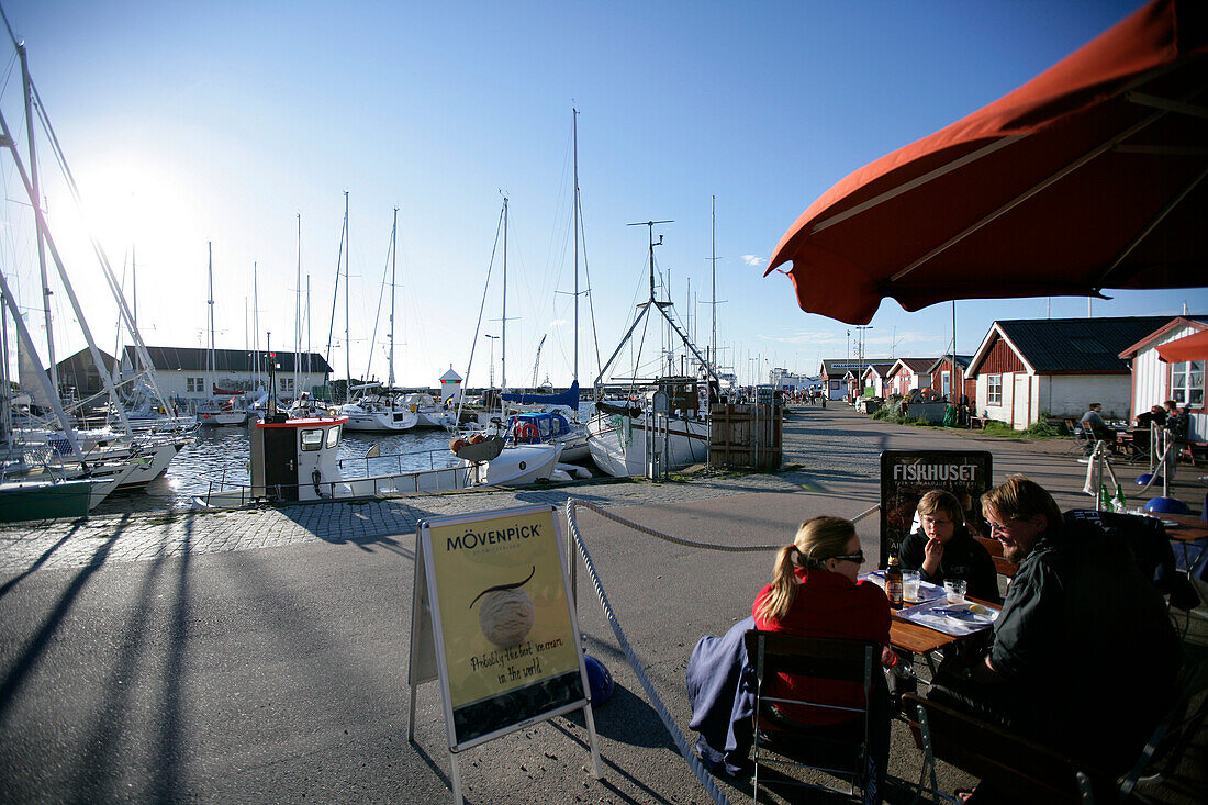 Three people sitting in a cafe at the harbour, Torekov, Skane, Sweden