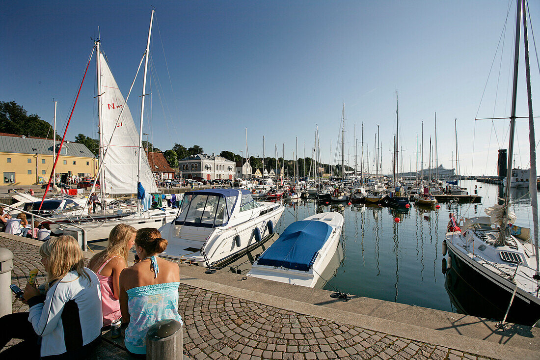 Drei Mädchen, Frauen sitzen beim Hafen, Visby, Gotland, Schweden