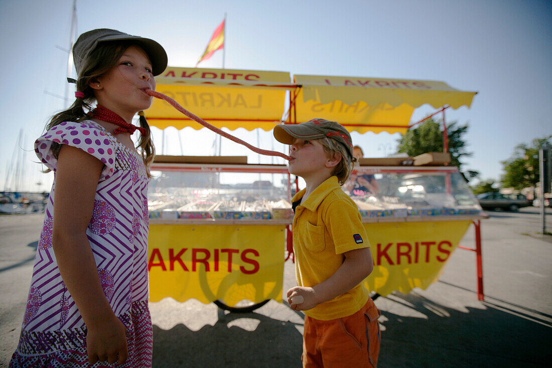 Boy and girl eating candy, typical liquorice, Visby, Gotland, Sweden