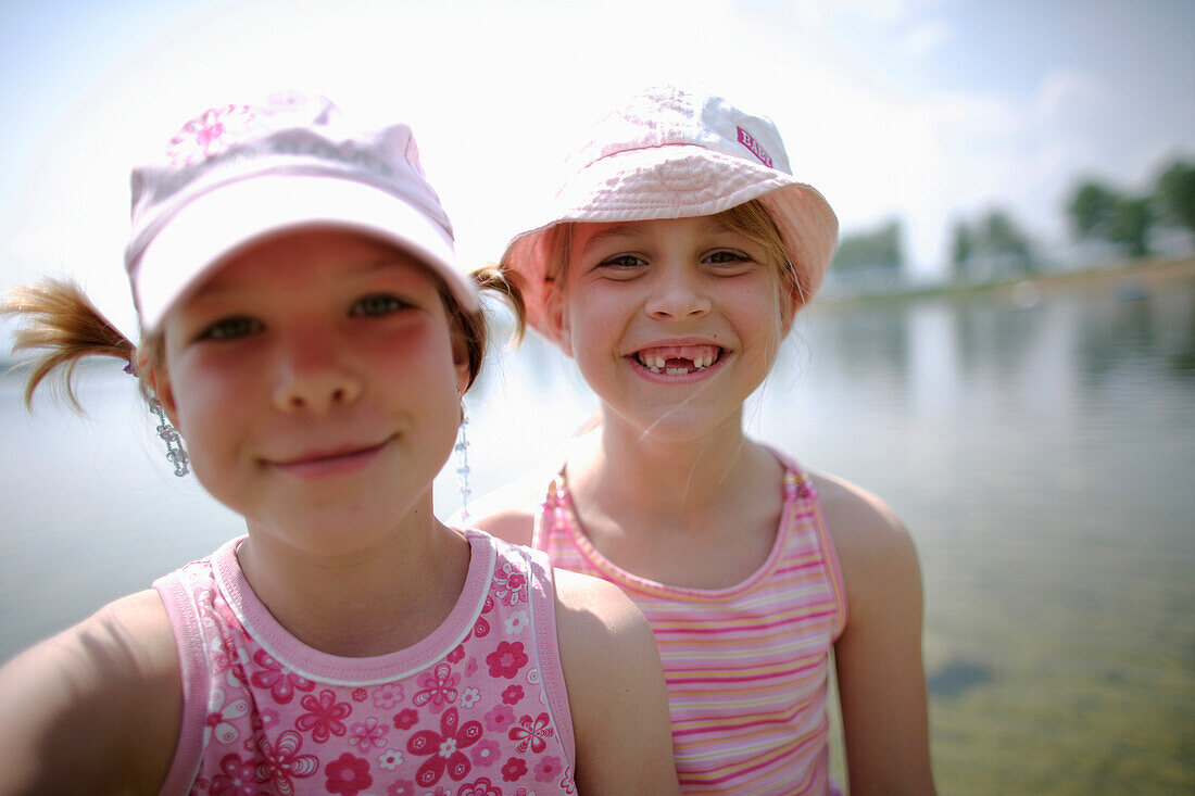 Two girls (7-8 years) smiling at camera, Lake Staffelsee, Upper Bavaria, Germany