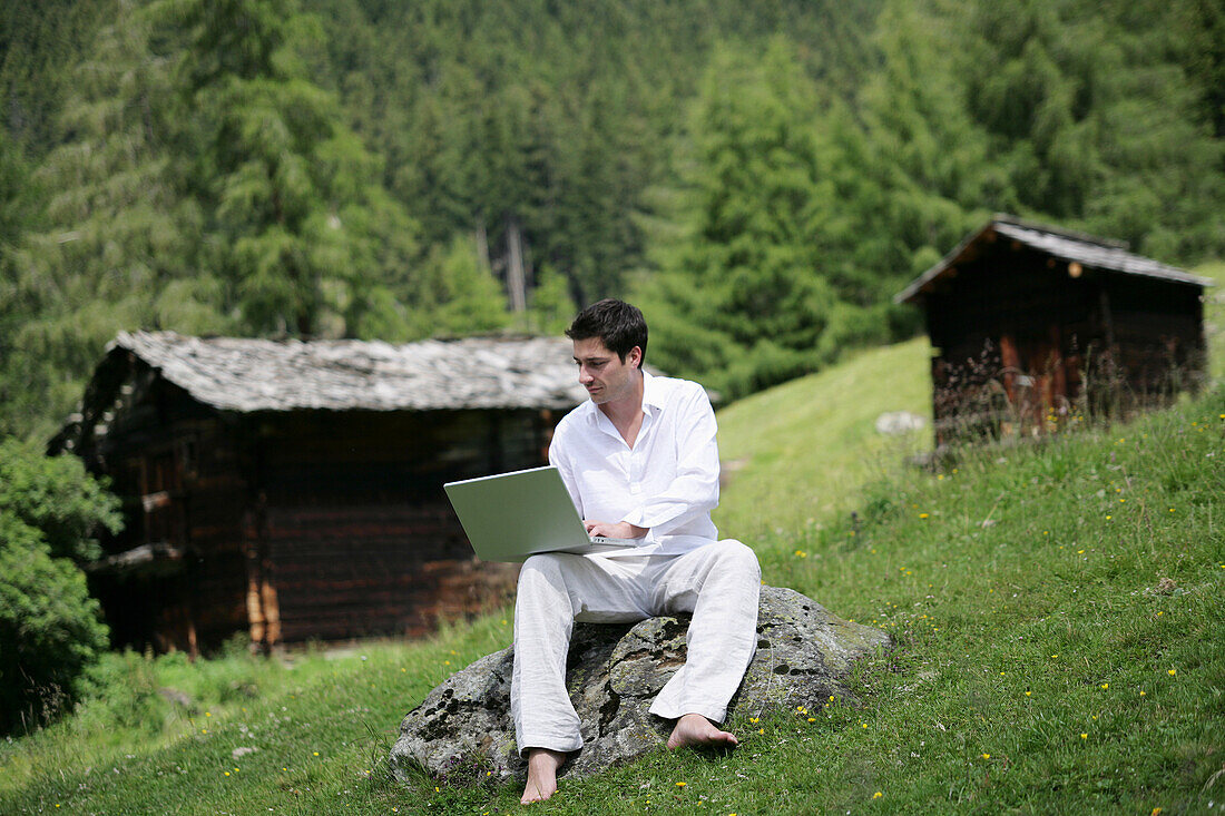 Mid adult man using a laptop, Heiligenblut, Hohe Tauern National Park, Carinthia, Austria