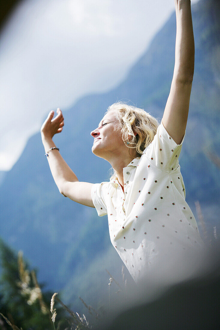 Frau streckt sich mit geschlossenen Augen, Heiligenblut, Nationalpark Hohe Tauern, Kärnten, Österreich