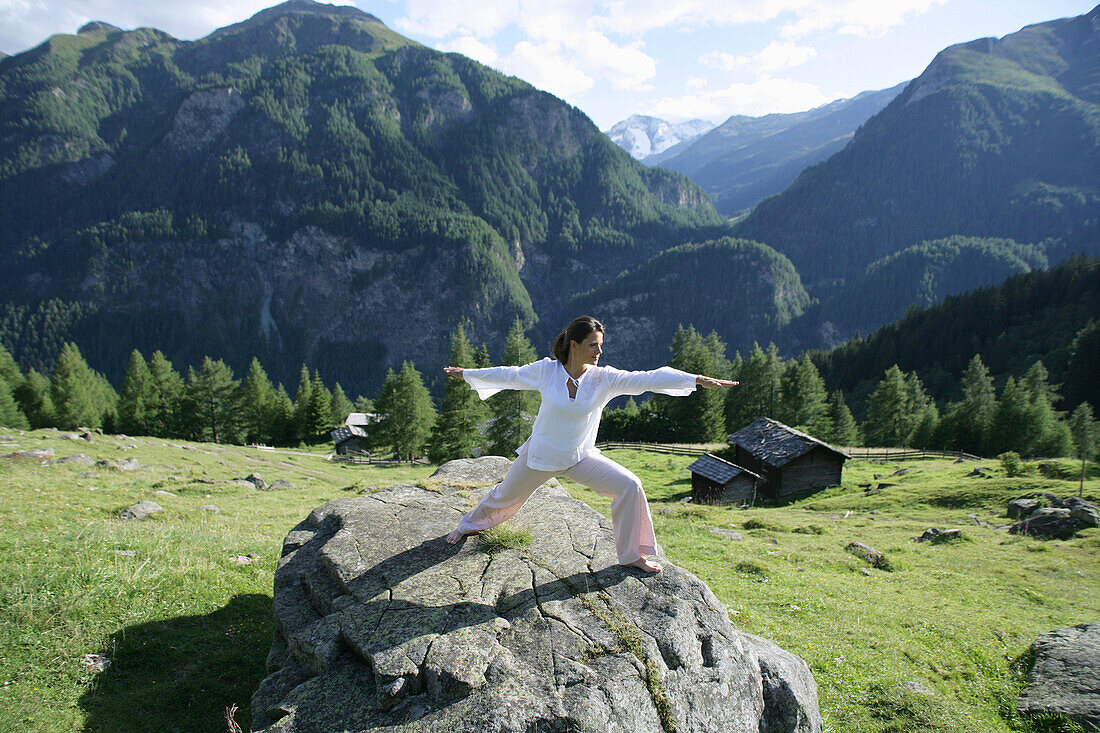 Frau macht Yoga auf einem Felsen, Heiligenblut, Nationalpark Hohe Tauern, Kärnten, Österreich