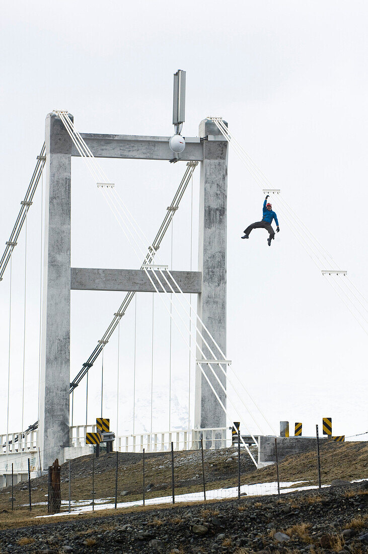 Man climbing on bridge construction, Skaftafell National Park, Iceland