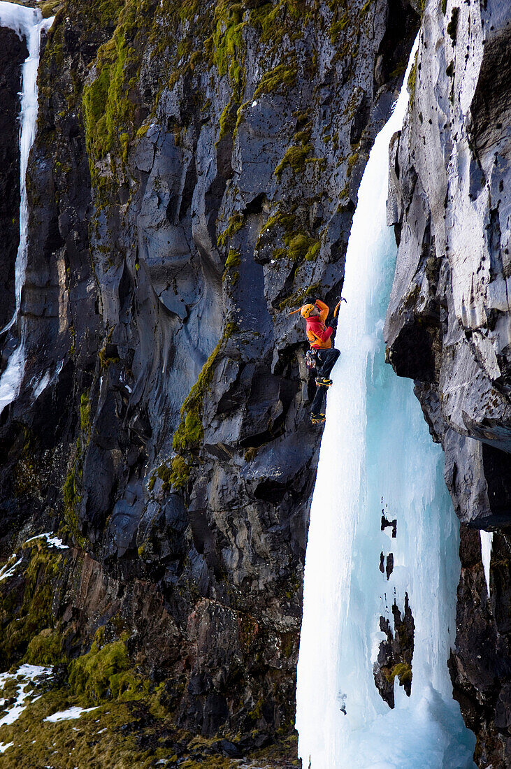 Ice climber on frozen waterfall, Iceland