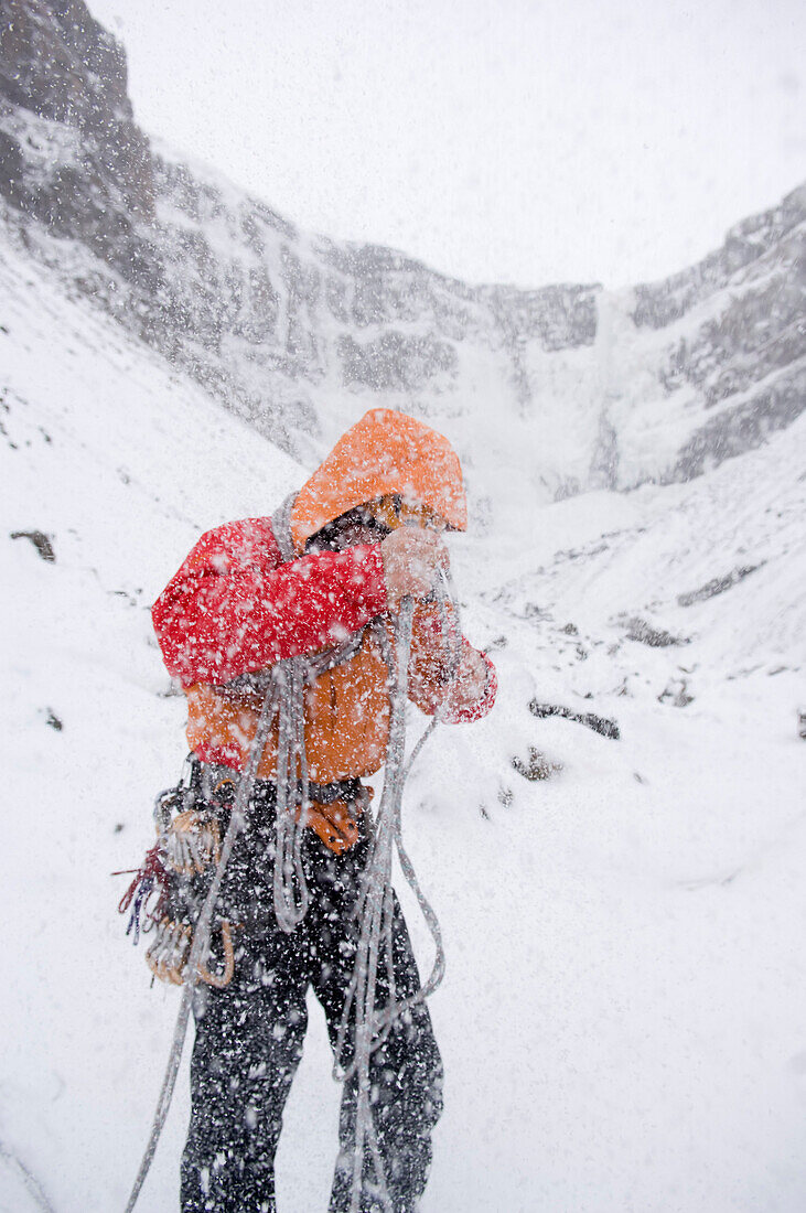 Ice climber in snow storm, Hengifoss, Austurland, Iceland