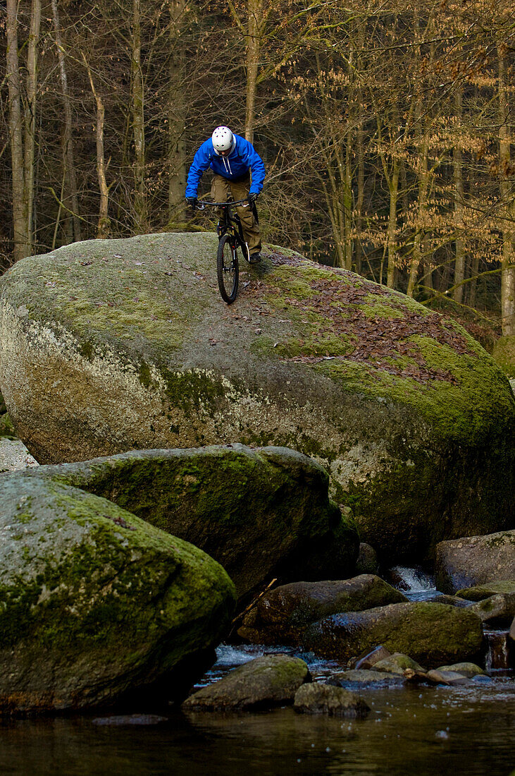 Trial biker on rock at river, Muehlviertel