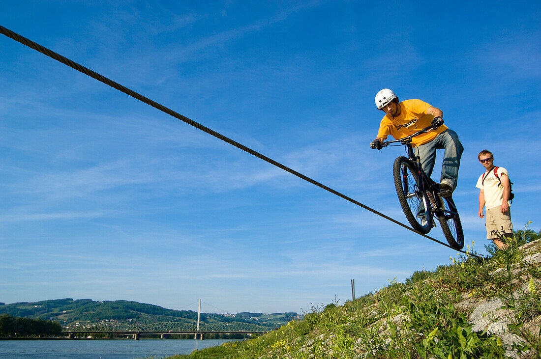 Trialbiker auf Stahlseil an der Donau, Linz