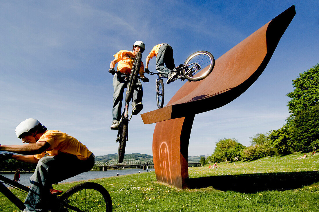 Trialbiker auf einer Eisenskulptur im Park, Linz, Oberösterreich, Österreich