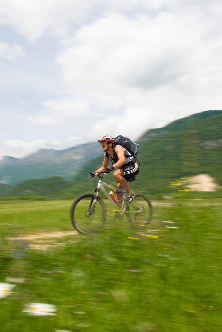 Mountainbiker fährt über Wiese, Slowenien