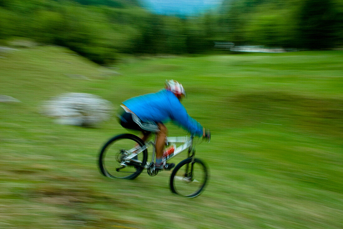 Mountainbiker fährt bergab über eine Wiese, Nationalpark Triglav, Slowenien