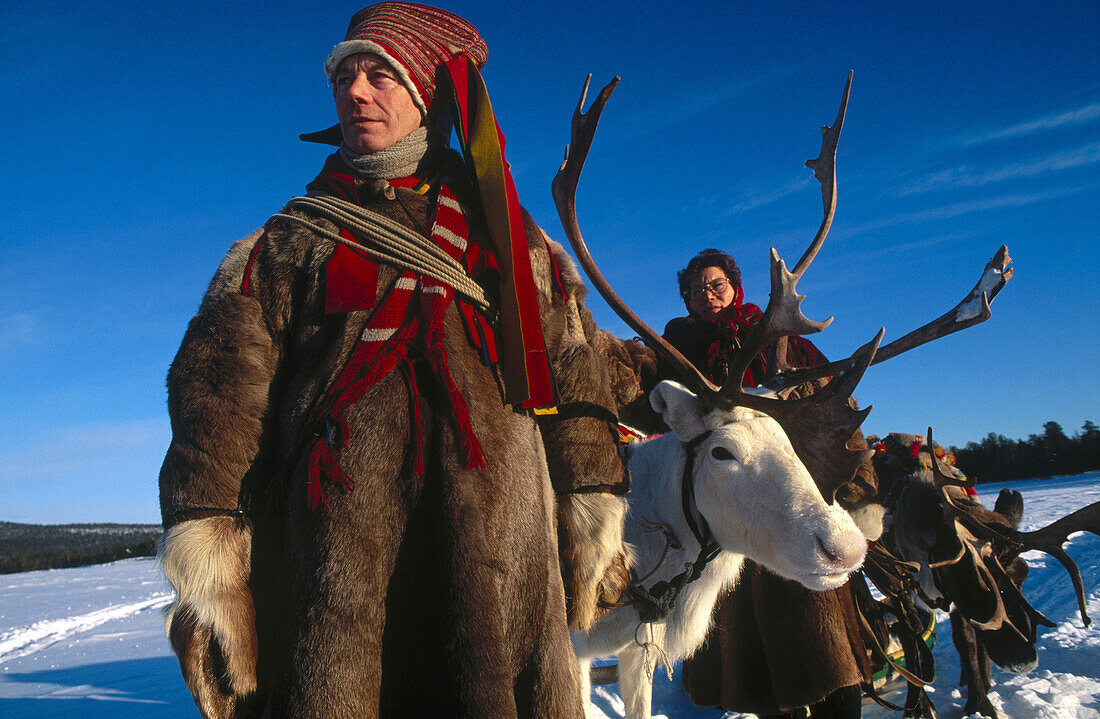 Lapps with traditional costumes and reindeer. Inari lake. Lapland. Finland.