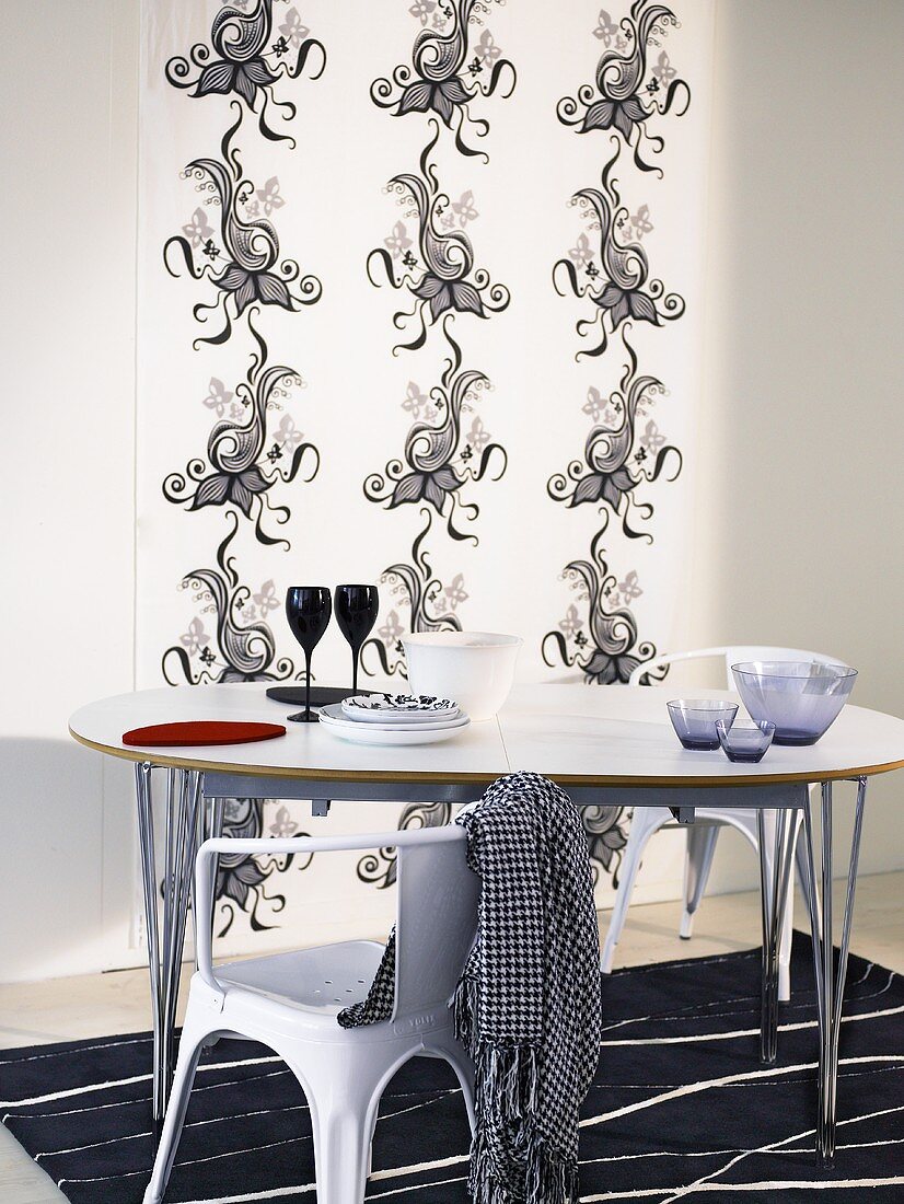 Chair and dining table with metal frame in front of a wall hanging with black and white Asian design
