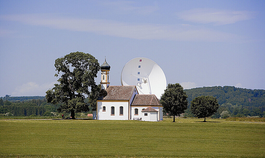 Satellite dish and St. Johann Chapel. Upper Bavaria, Raisting, Germany.