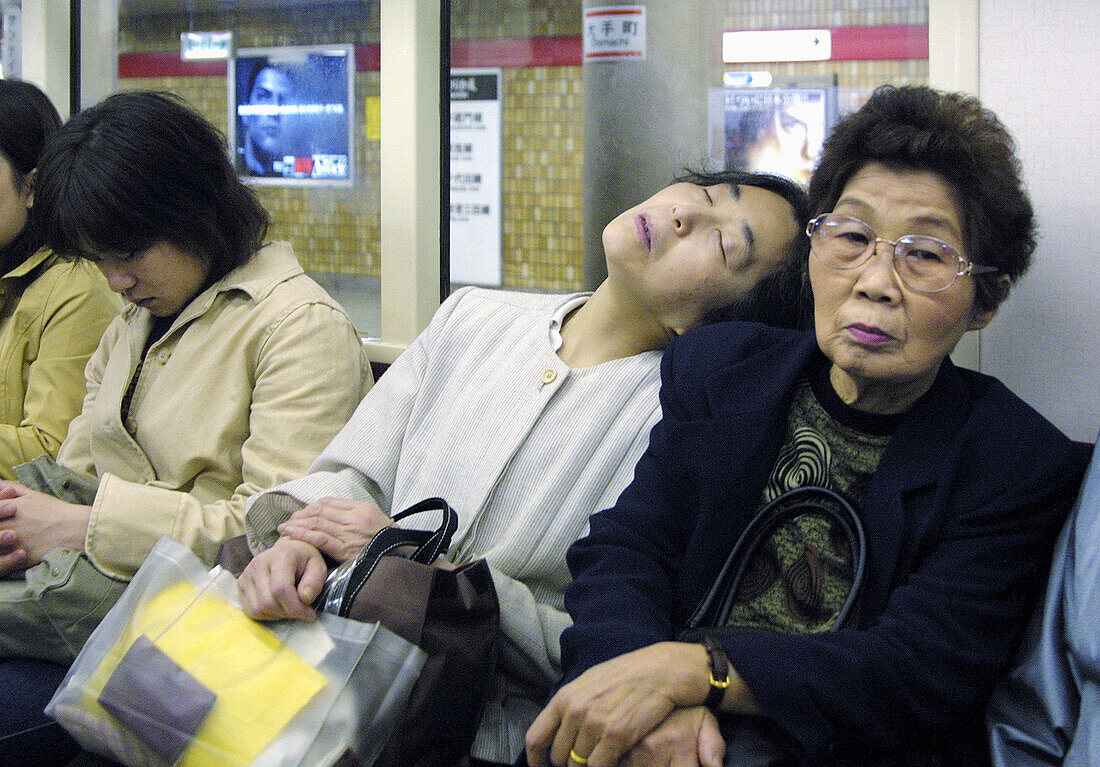 People often sleep on the trains. Here a woman is sleeping on an other womans shoulder in the subways of Tokyo, Japan.
