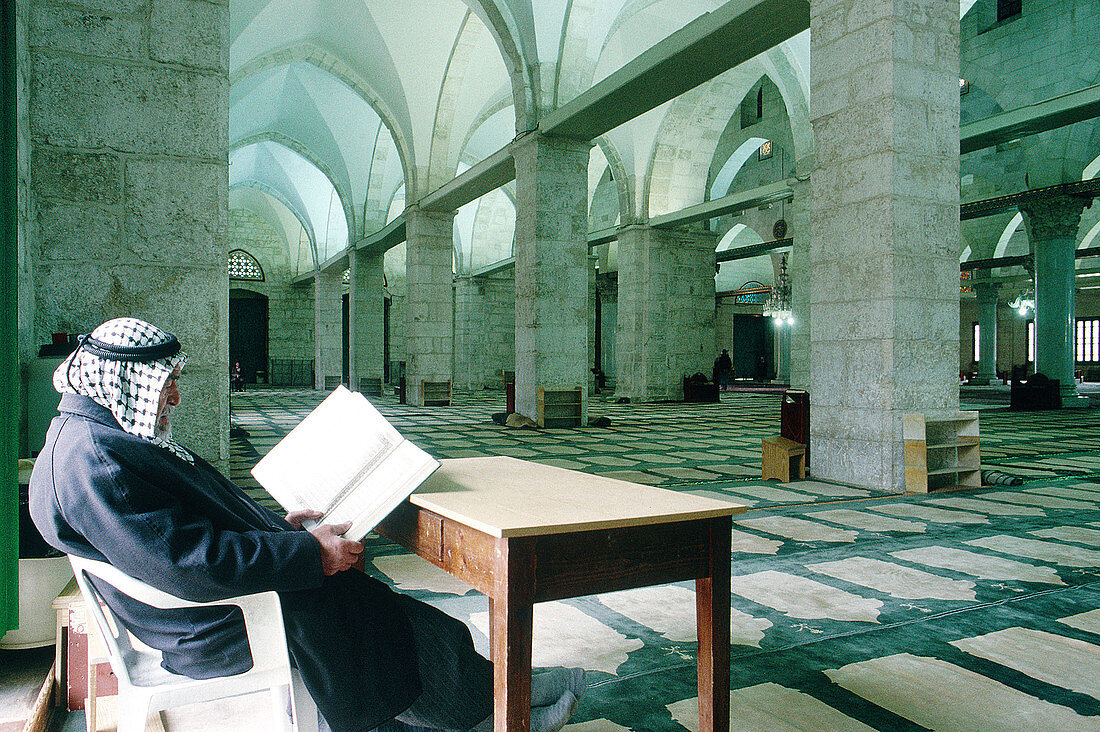 Man in Palestinian keffieh reading Coran at mosque. Jerusalem. Israel
