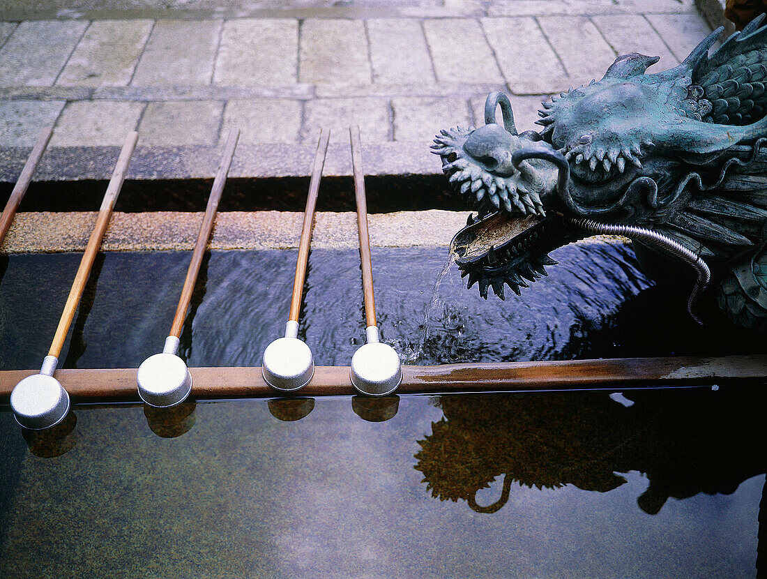 Fountain, water dippers and dragon statue at entrance to Shinto shrine. Kyoto. Japan