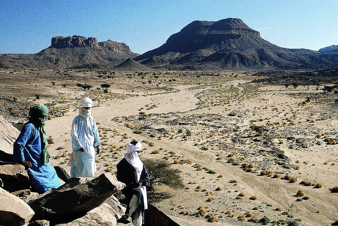 Tuaregs on a hill in front of Atakor Mountains. Hoggar area, South Sahara. Algeria