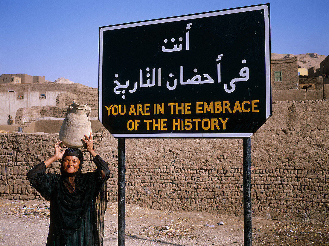 Woman carrying jar on her head in Deir el-Bahri. Nile West Bank, Luxor. Egypt