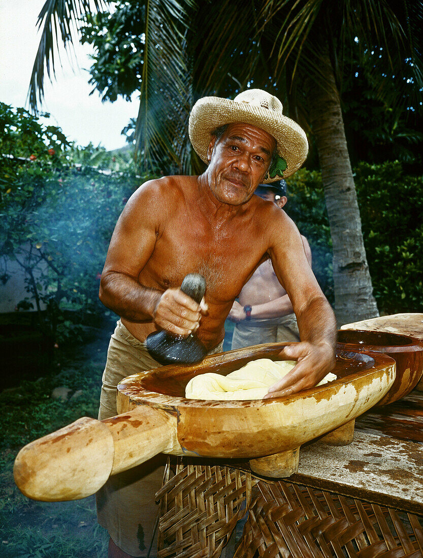 Man preparing fresh poi poi (smashed uru or breadfruit) which used to be the main food of ancient marquesans. Hakehau bay, Ua-Pou island. Marquesas archipelago. French Polynesia