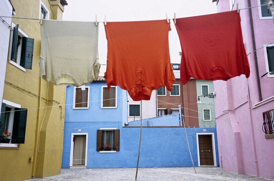 Colorful drying laundry on piazetta (small square). Island of Burano. City of Venice. Italy
