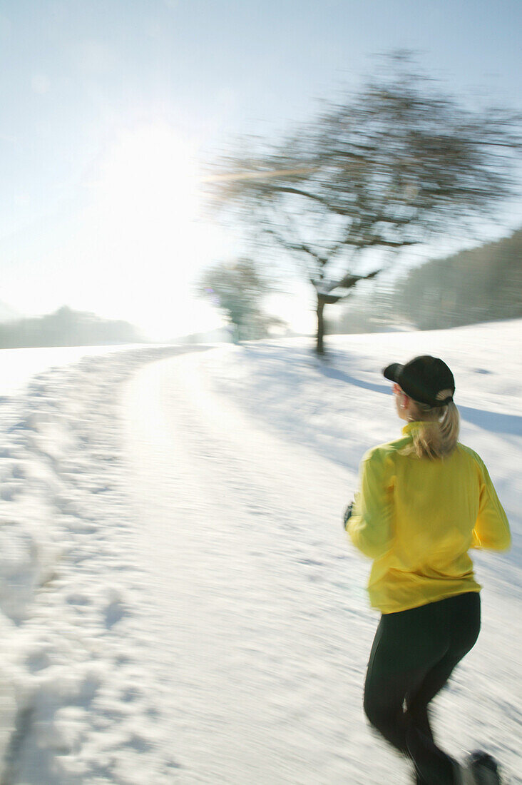 Frau joggt über verschneiten Weg, Steiermark, Österreich