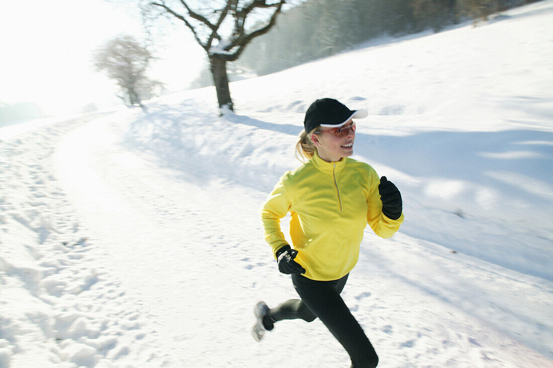 Frau joggt über verschneiten Weg, Steiermark, Österreich