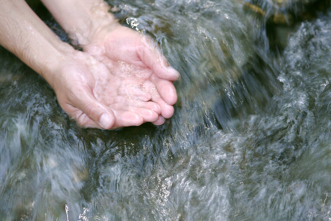 Hände im fließendem Wasser von einem Bach, Steiermark, Österreich