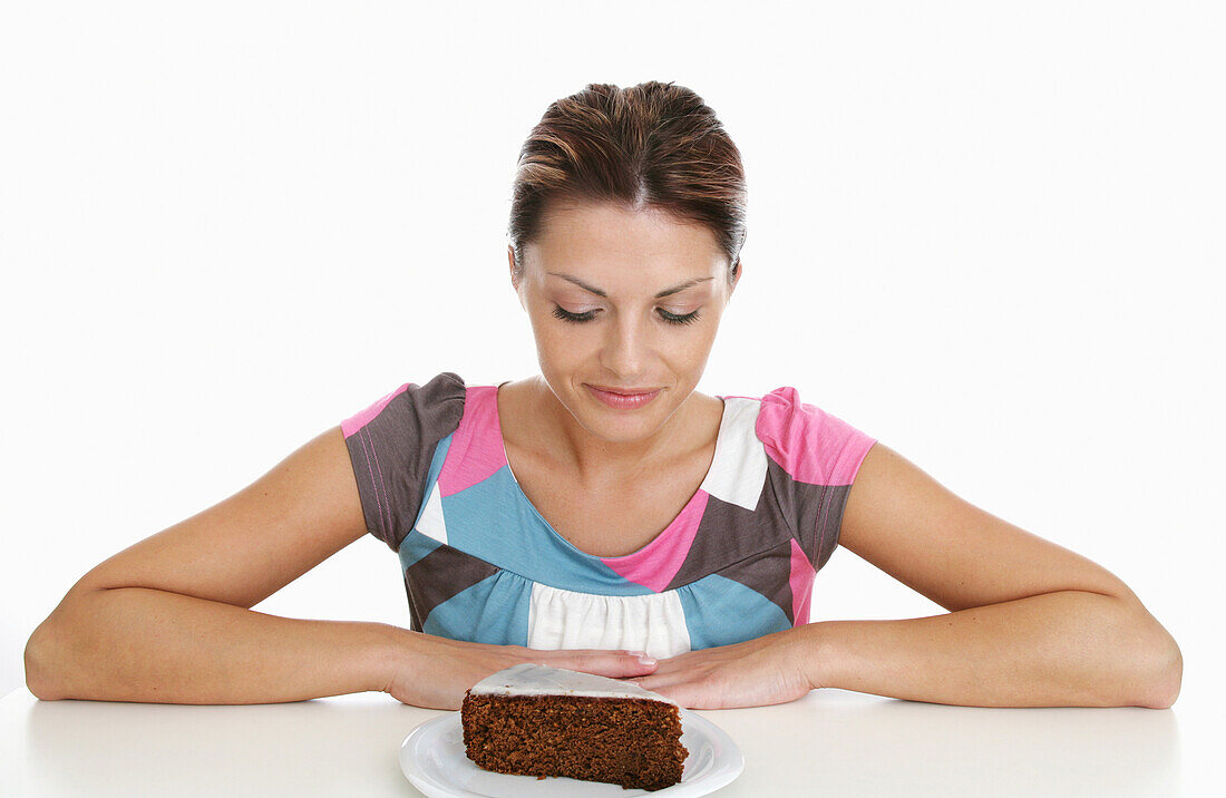Frau mittleren Alters blickt auf ein Stück Schokoladenkuchen, Steiermark, Österreih