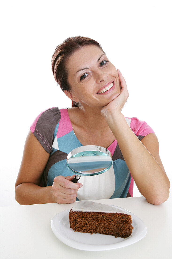 Woman observing chocolate cake through magnifying glass, Styria, Austria