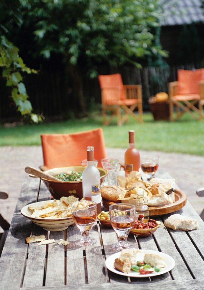 Gedeckter Tisch mit Antipasti und Salat im Garten