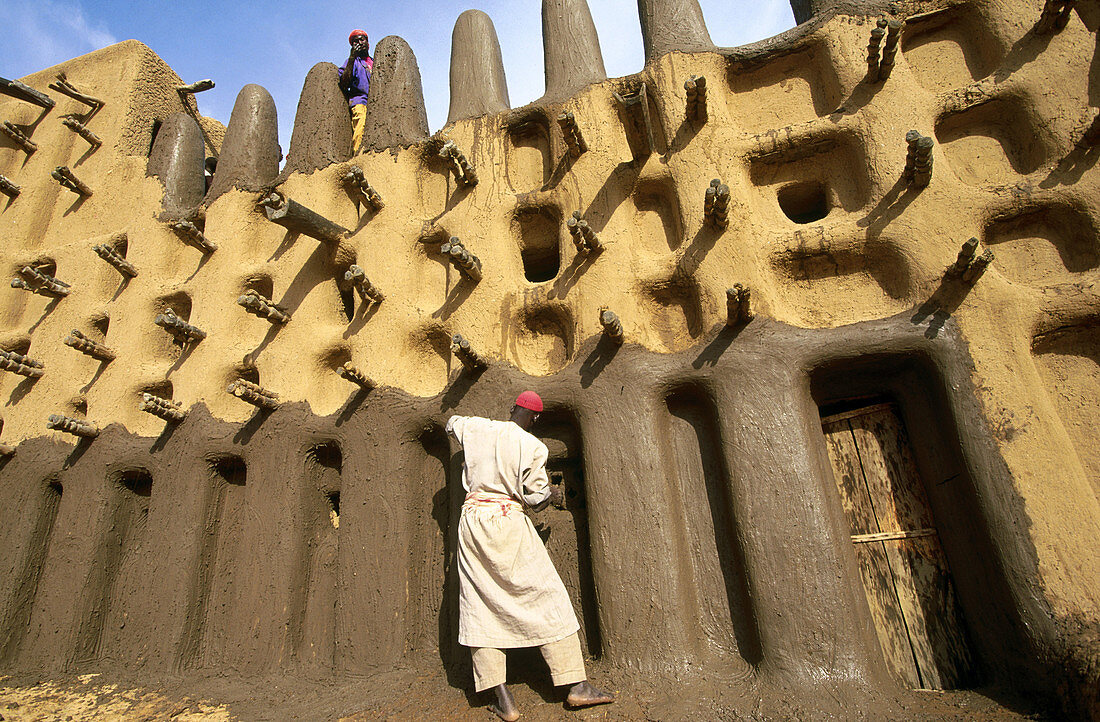 Man plastering mosque with mud, Dogon Valley, Mali
