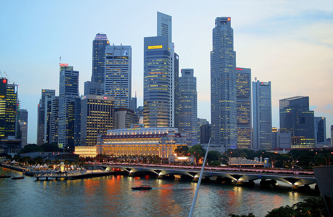 Evening view of the Singapore skyline from Marina Bay, with Esplanade Bridge, Fullerton Hotel and Merlion. Singapore.
