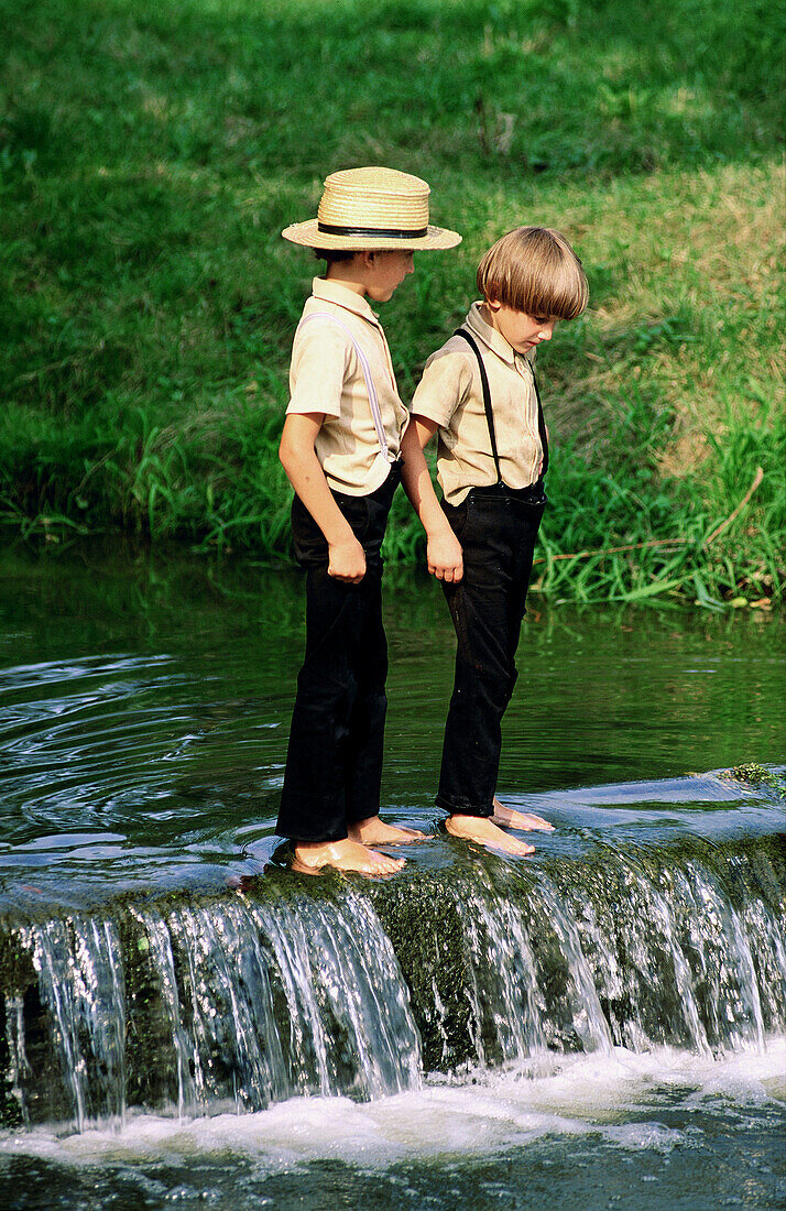 Two amish boys playing in a small river, Lancaster County. Pennsylvania, USA