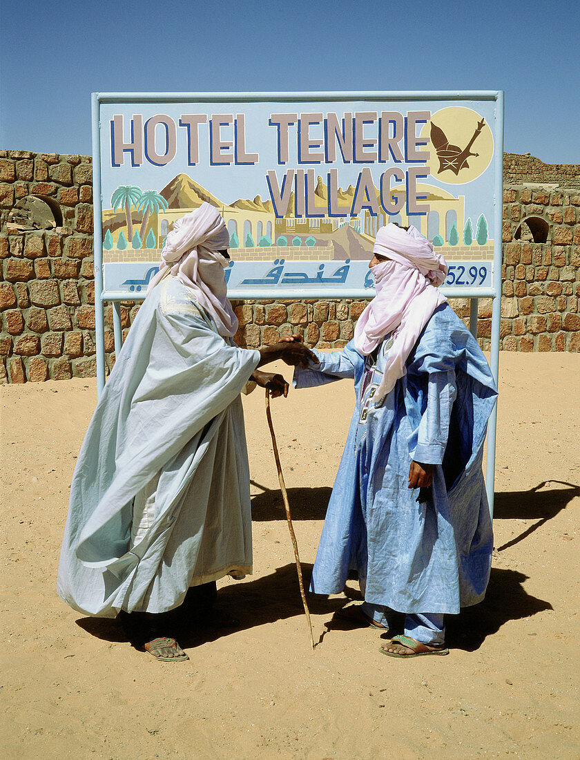 Tuareg men meeting and greeting, wearing the white chech (local turban or veil). Sahara desert. South Algeria