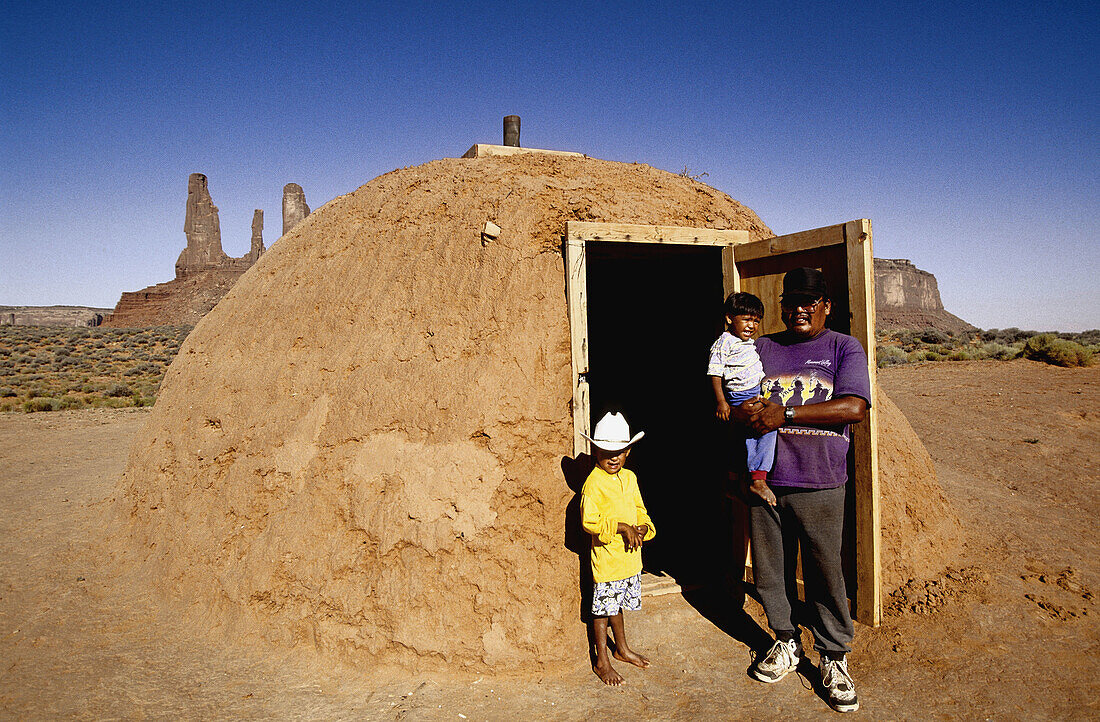 Father and his two children. Traditional Hogan (navajo mud hut) by the three sisters peaks. Monument valley, Navajo reservation. Utah. United states (USA)
