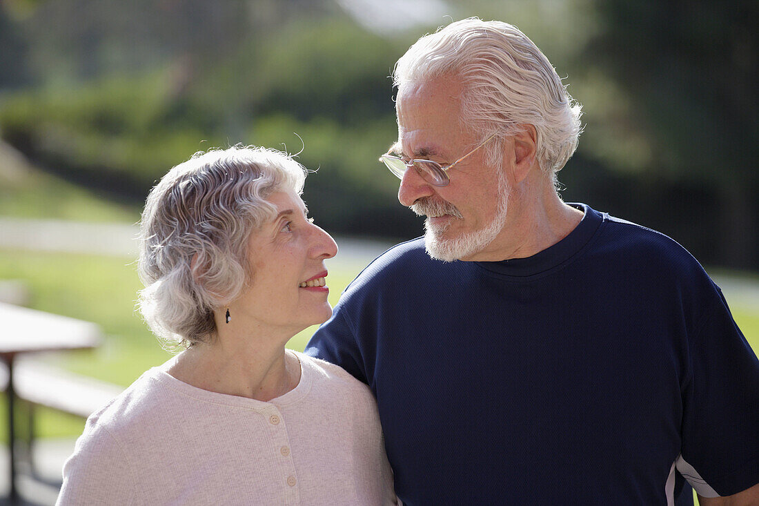 Portrait of active senior couple looking lovingly at each other in an outdoor park.