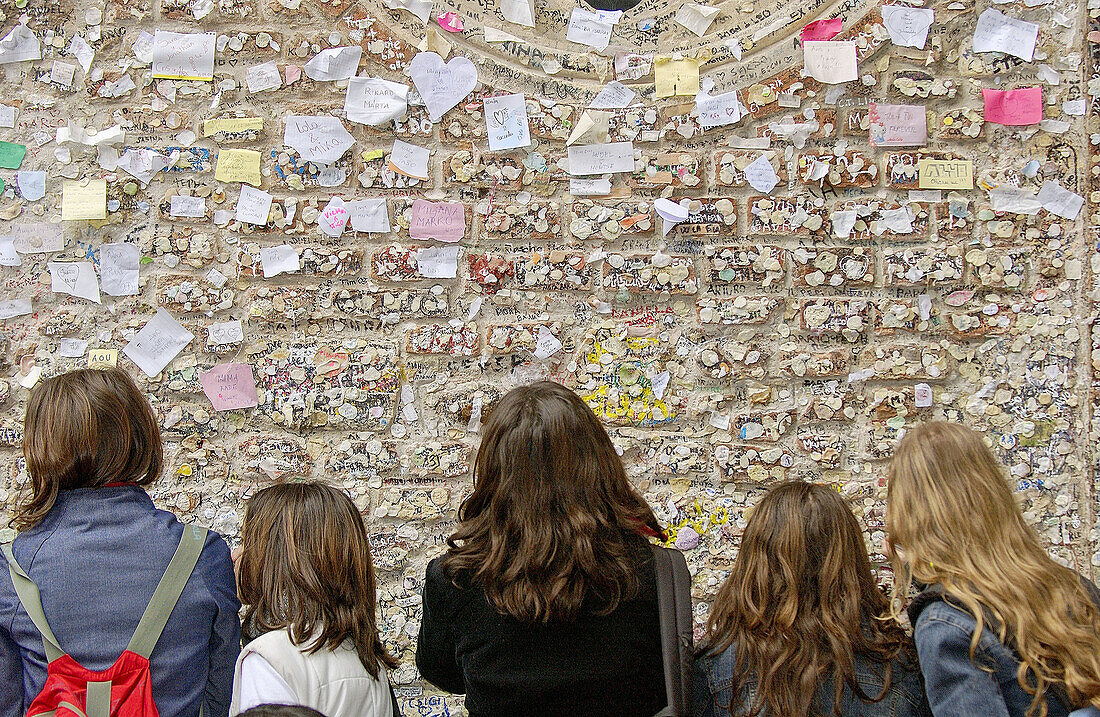 Teen girls looking at writings on courtyard of Juliet s House walls. Verona. Veneto, Italy